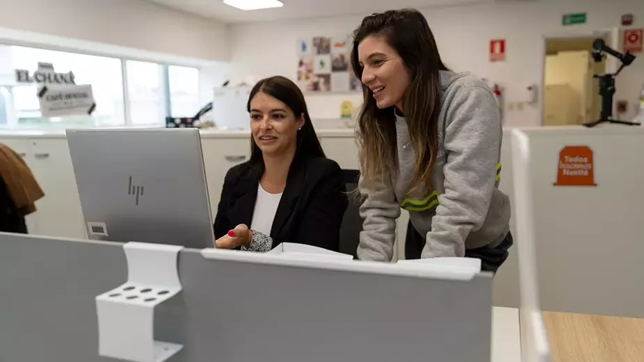 Nestlé employees collaborating at a computer workstation in a modern office environment